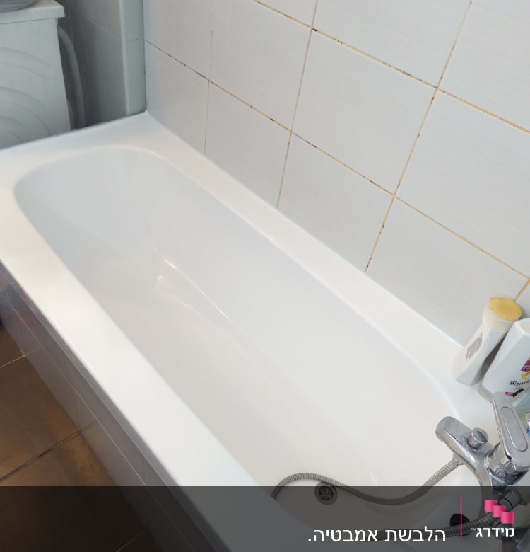 אמבטיה לבנה עם ברז מתכת וקיר אריחים לבנים